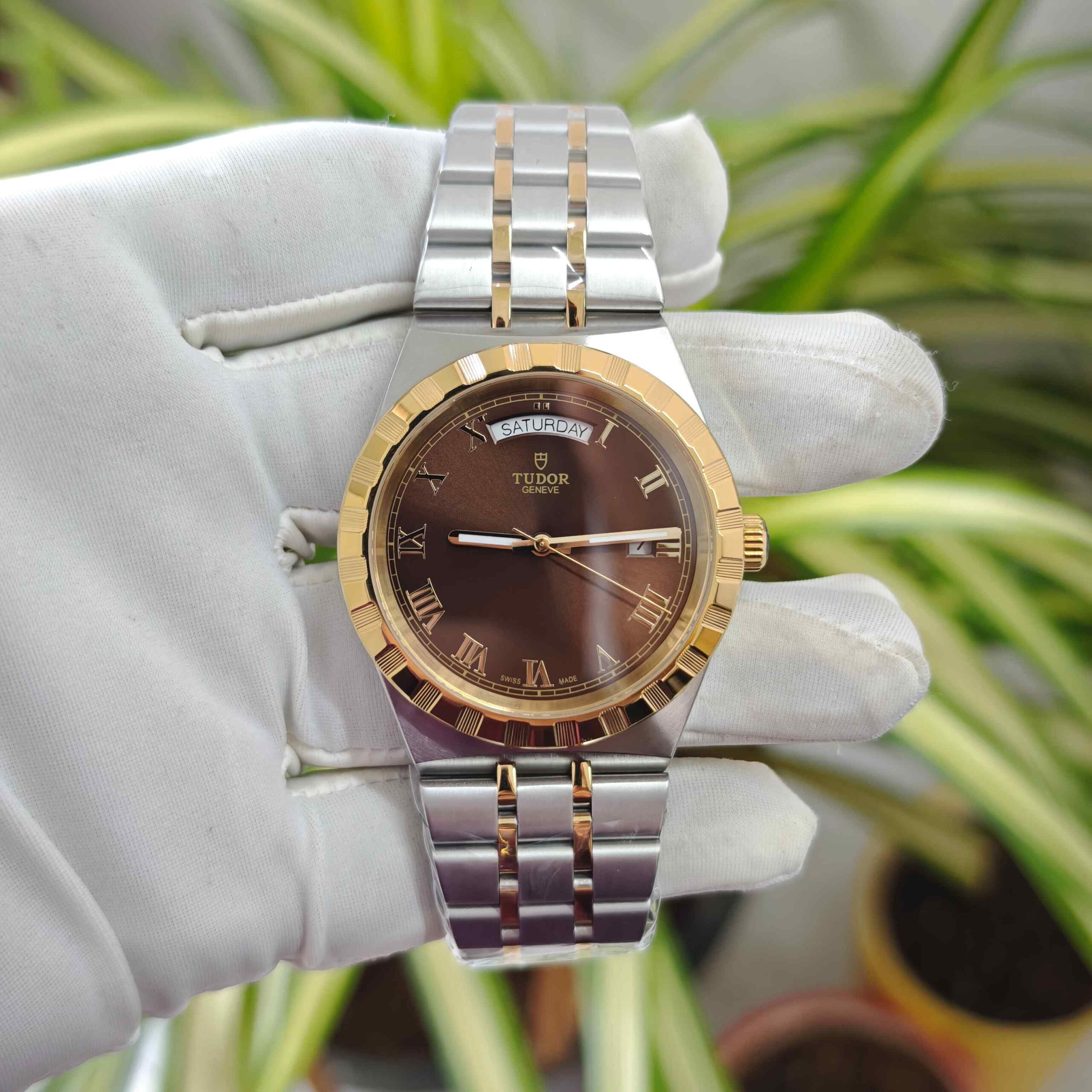 Tudor Royal Day-Date dual tone luxury watch featuring a gold-tone bezel, rich brown dial, elegant Roman numeral markers, and a stylish stainless steel and gold-tone bracelet.