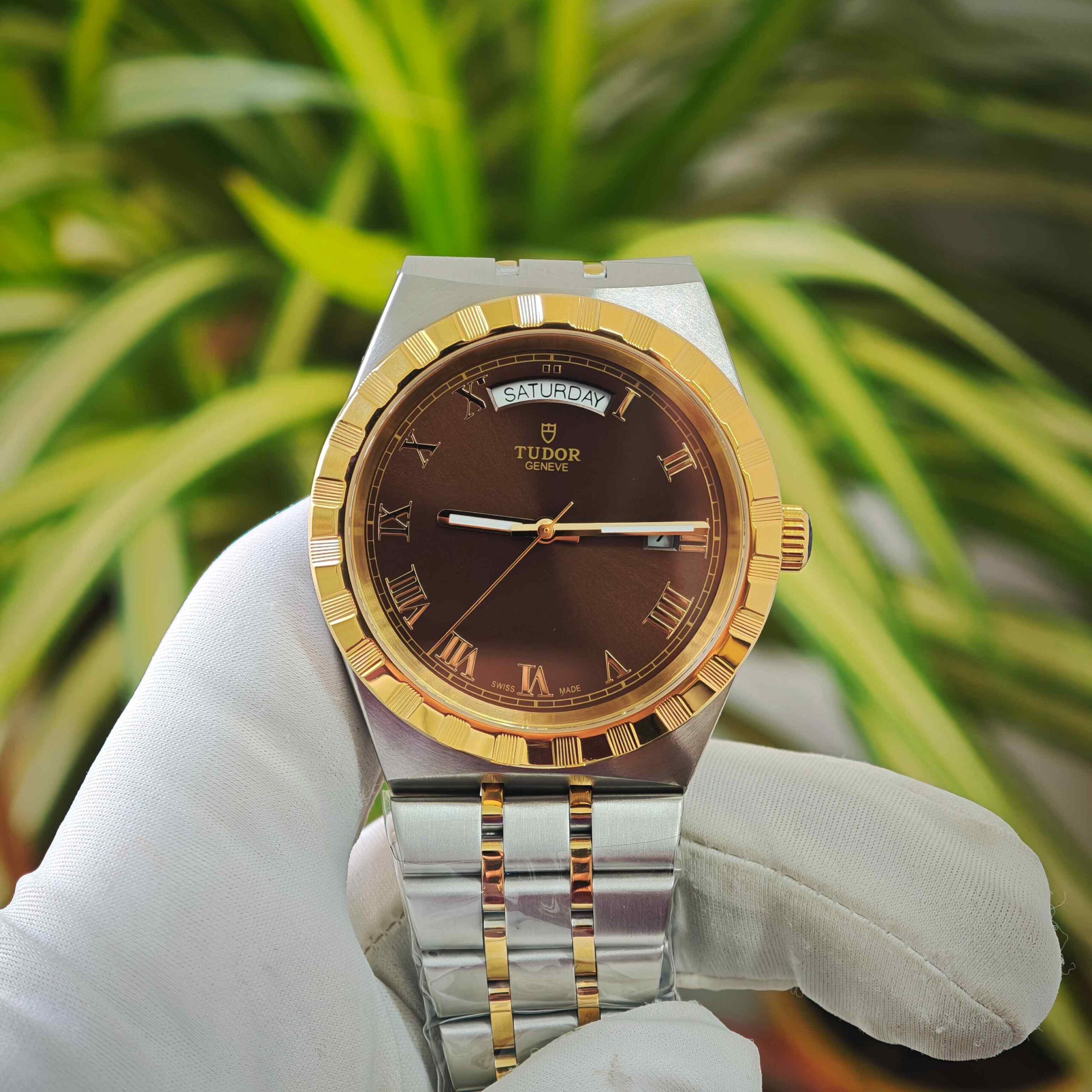 Tudor Royal Day-Date dual tone luxury watch featuring a gold-tone bezel, rich brown dial, elegant Roman numeral markers, and a stylish stainless steel and gold-tone bracelet.