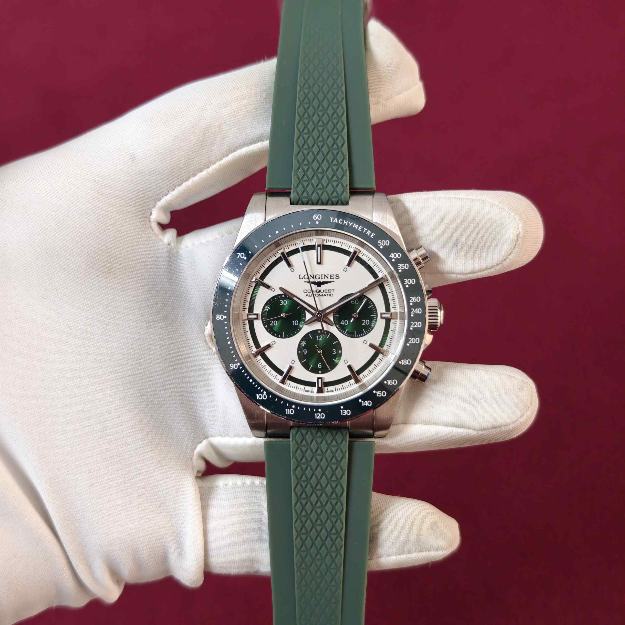 Longines Conquest Chronograph automatic watch featuring a stainless steel case, clean white dial, chronograph sub-dials, and green rubber strap.