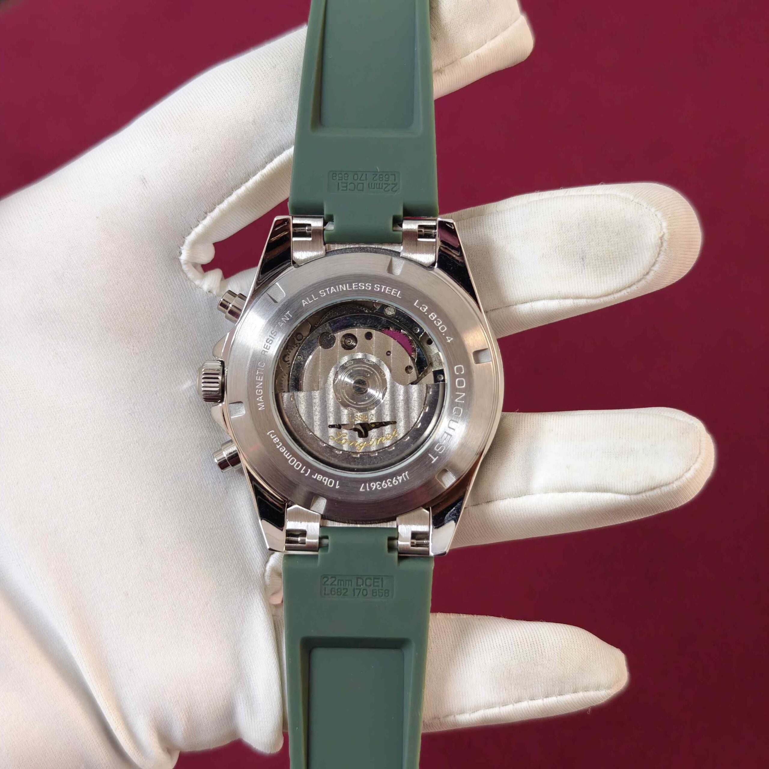 Longines Conquest Chronograph automatic watch featuring a stainless steel case, clean white dial, chronograph sub-dials, and green rubber strap.