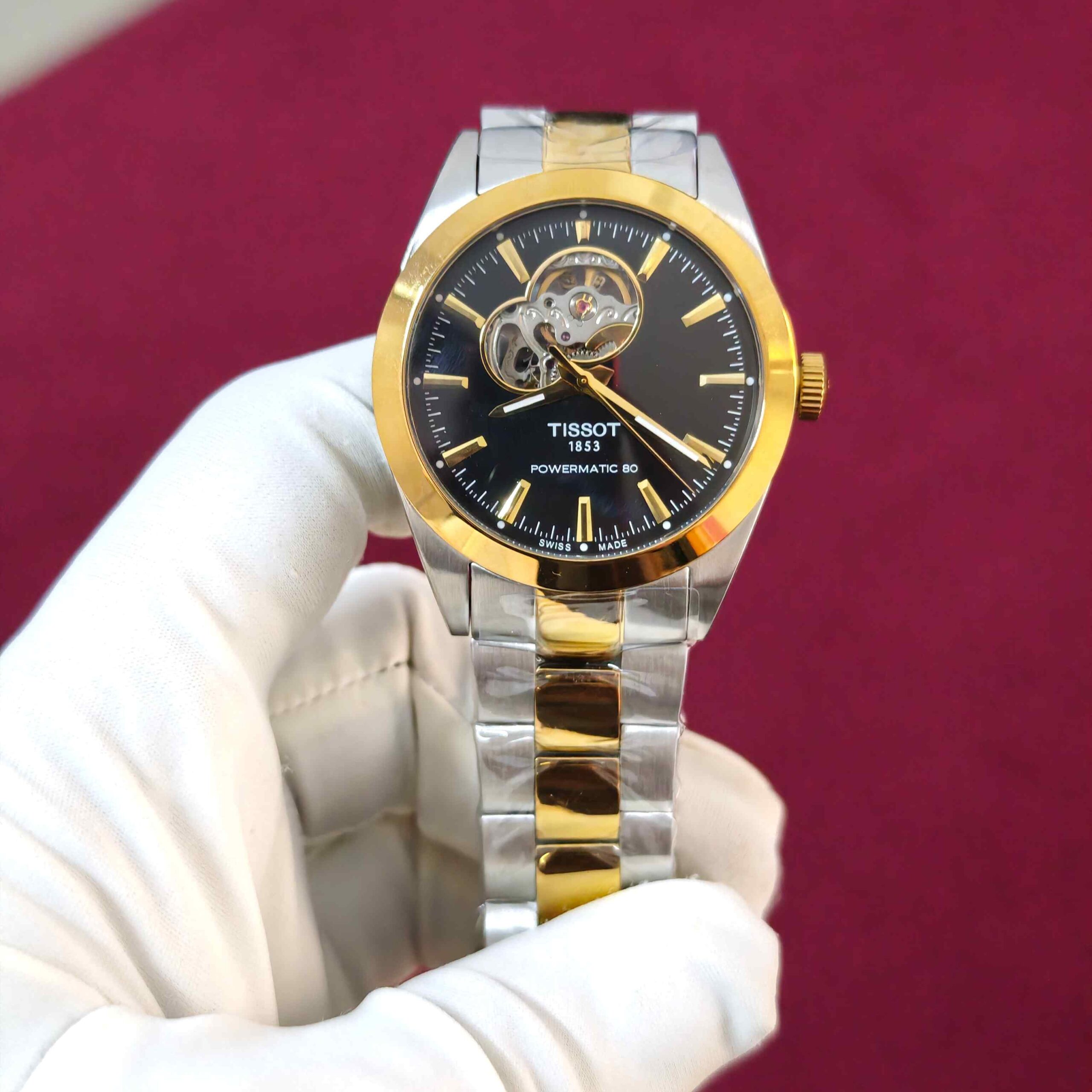 Tissot Gentleman Powermatic 80 Open Heart automatic watch featuring a black dial, gold dual-tone stainless steel bracelet, elegant gold accents, and visible mechanical movement.